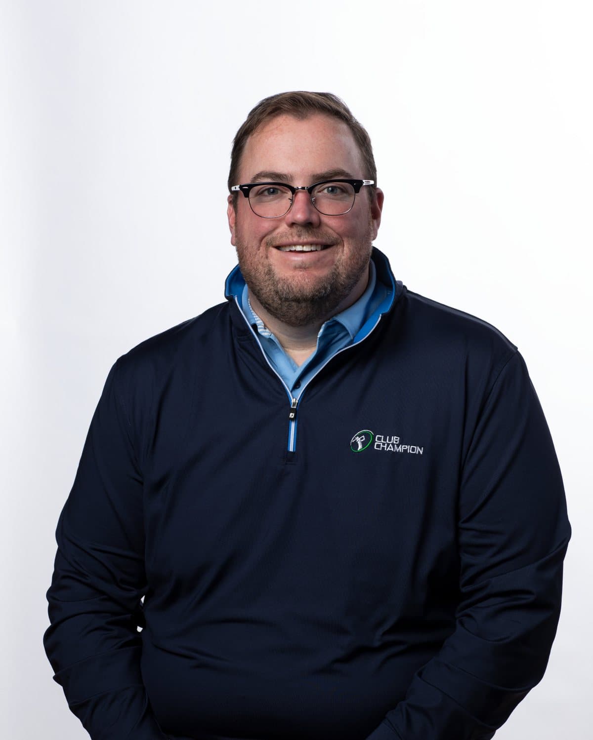 Nick Sherburne, founder of Club Champion, seated studio portrait in a Club Champion quarter-zip